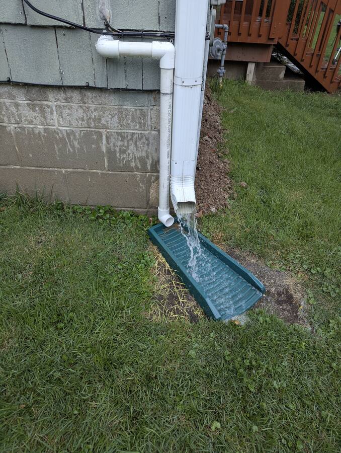 Sump discharge routed outside to a splash block — not into the sanitary sewer